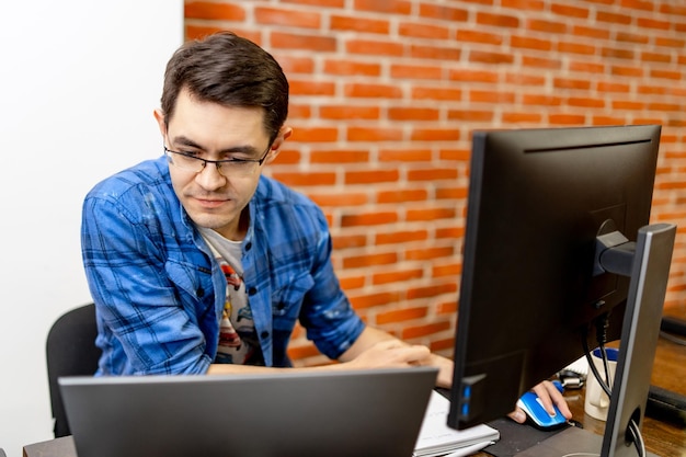 Jovem sentado no escritório e trabalhando no computador desktop empresário olhando para o monitor do computador enquanto trabalhava no escritório