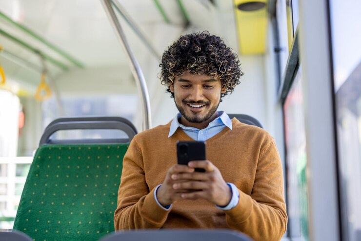 Foto jovem sentado no ônibus usando smartphone sorrindo e envolvido em conteúdo digital vestimenta casual e