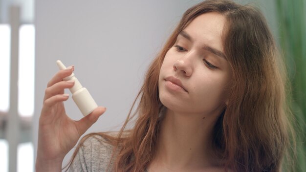 Jovem sentindo nariz entupido enquanto alergia e pulverizando spray nasal