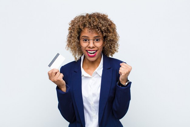 Jovem, sentindo-se chocado, animado e feliz, rindo e comemorando o sucesso, dizendo uau! com cartão de crédito