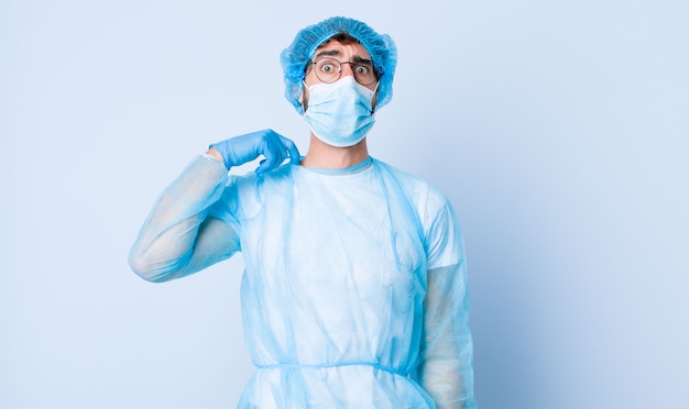 Jovem, sentindo-se estressado, ansioso, cansado e frustrado, puxando o pescoço da camisa, olhando frustrado com o problema. conceito de coronavírus