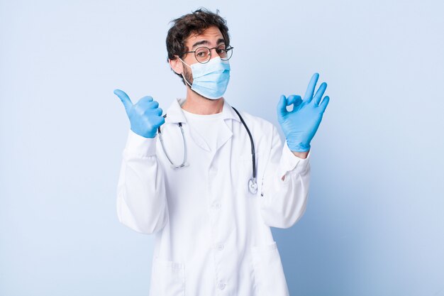 Jovem, sentindo-se feliz, espantado, satisfeito e surpreso, mostrando bem e polegares para cima gestos, sorrindo. conceito de coronavírus