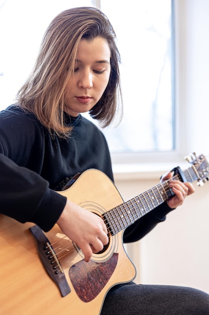 Jovem séria tocando violão em casa