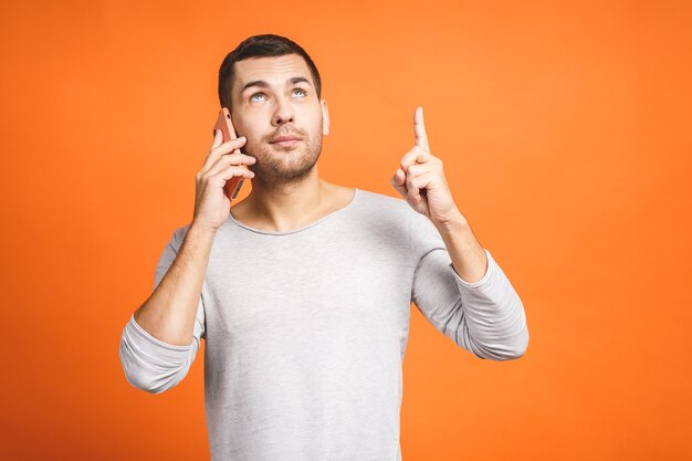 Foto jovem sério falando no celular isolado em um fundo laranja