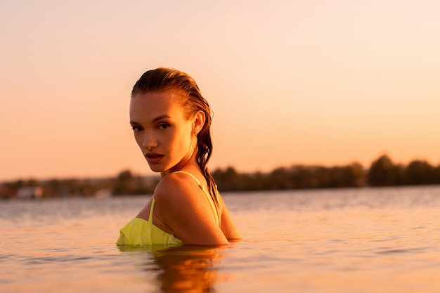 Jovem sexual no mar ao pôr do sol quente