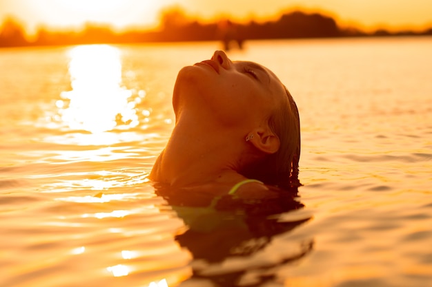 Jovem sexual no mar ao pôr do sol quente