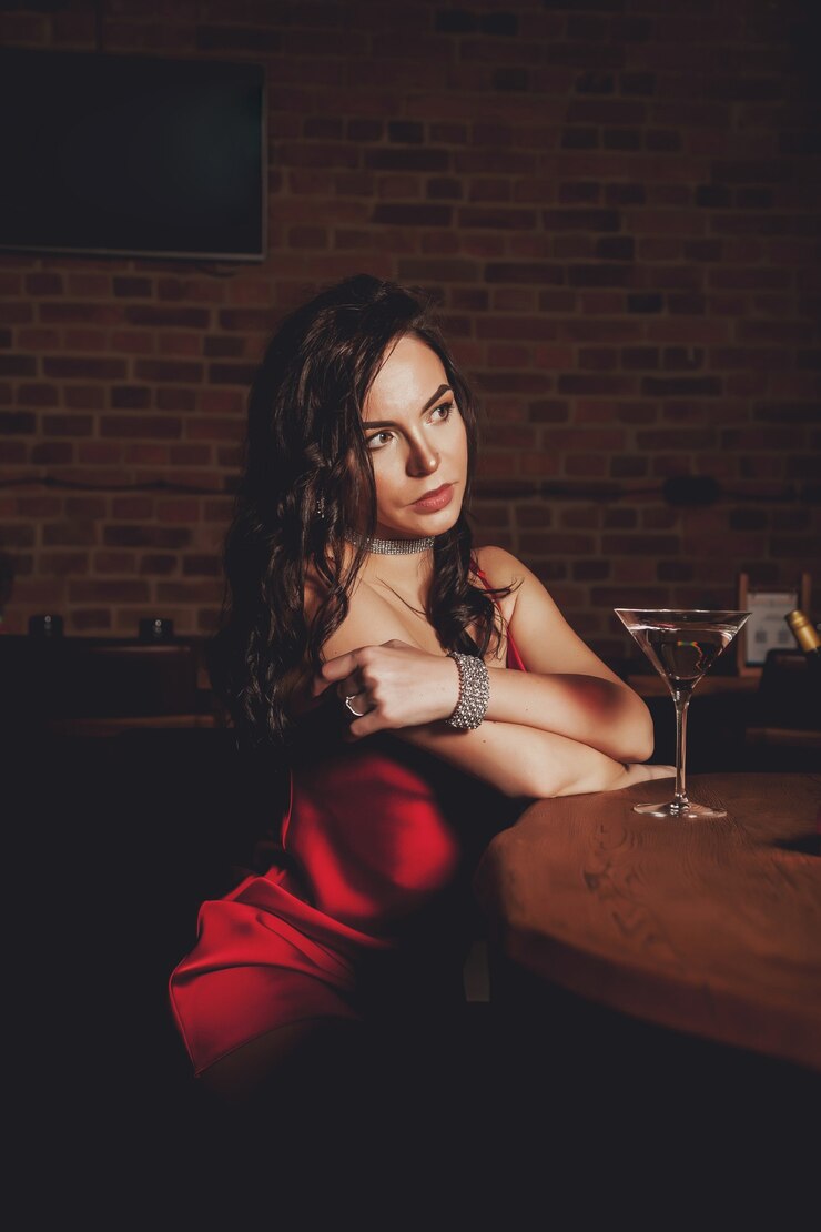 Foto jovem sexy fofa elegante em um lindo vestido vermelho brilhante em um restaurante de fundo escuro