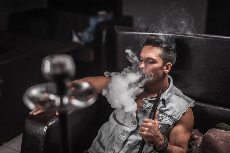 Foto jovem sexy fumando narguilé e fumaça saindo da boca em restaurante árabe.