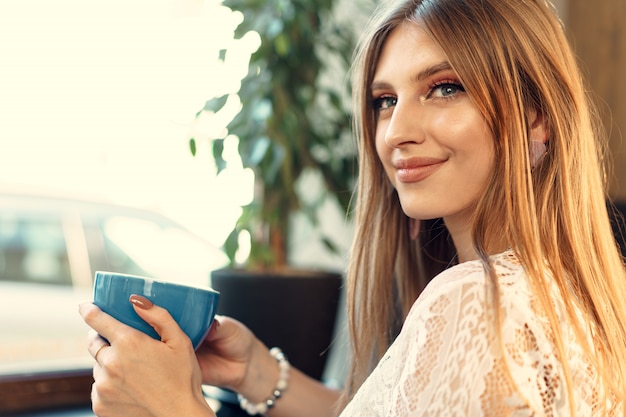 Jovem simpática, desfrutando de uma xícara de café em uma cafeteria