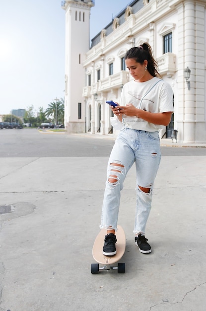 Jovem skatista checando seu celular na cidade