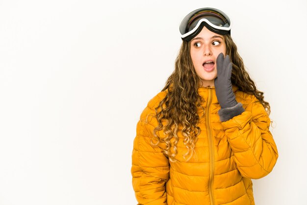 Jovem snowboarder caucasiana isolada está contando uma notícia secreta sobre a travagem e olhando para o lado