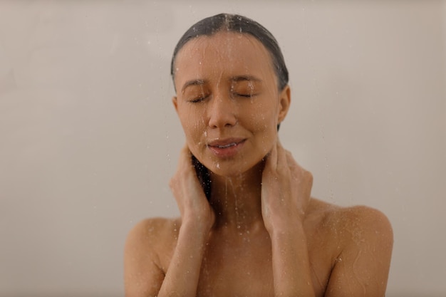 Jovem sob os pingos de água no banho de prazer Linda garota sob o spray de água no fundo isolado Cara feliz molhada