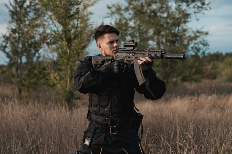 Foto jovem soldado de uniforme preto apontando um rifle de assalto
