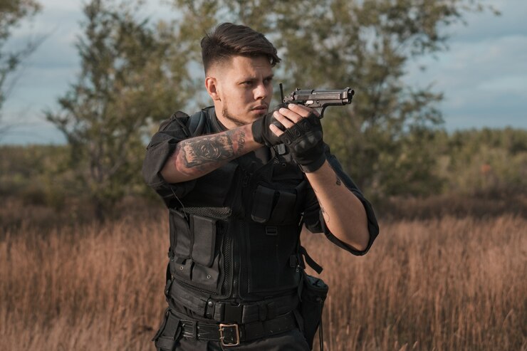 Foto jovem soldado de uniforme preto apontando uma pistola