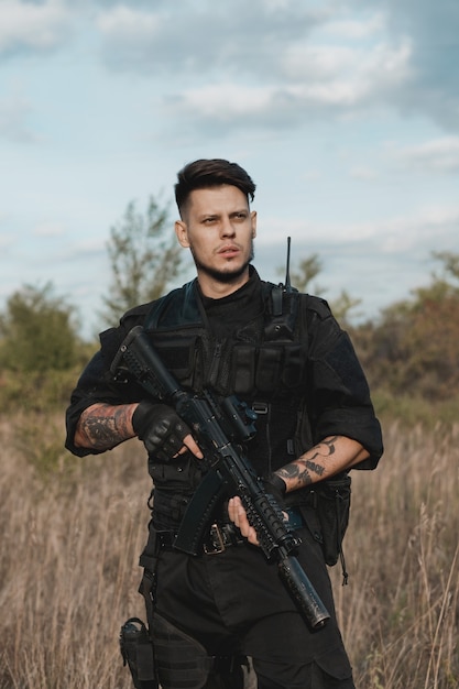 Jovem soldado de uniforme preto com um rifle de assalto