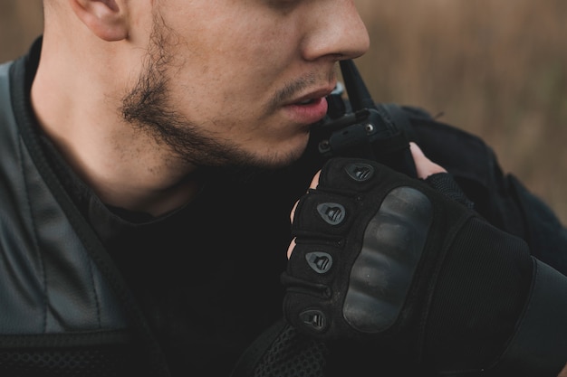 jovem soldado de uniforme preto reportando no rádio