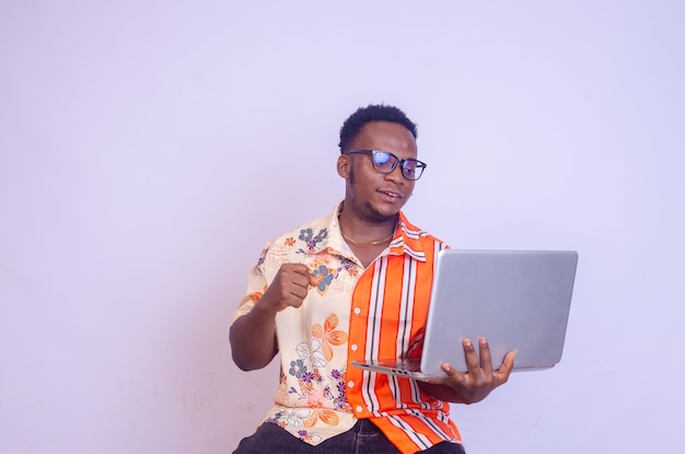 Jovem sorridente afro-americano sentado e usando computador portátil isolado sobre fundo branco