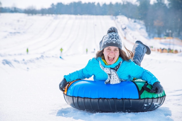 Jovem sorridente anda de trenó com tubos de neve atividade de inverno