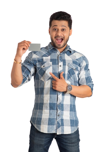 Foto jovem sorridente bonito posando com um cartão de crédito ou débito em fundo branco