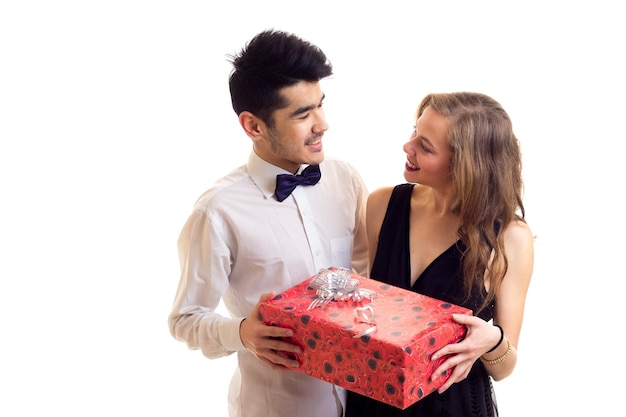 Jovem sorridente com cabelo preto e jovem mulher bonita com longos cabelos loiros, mostrando o presente vermelho