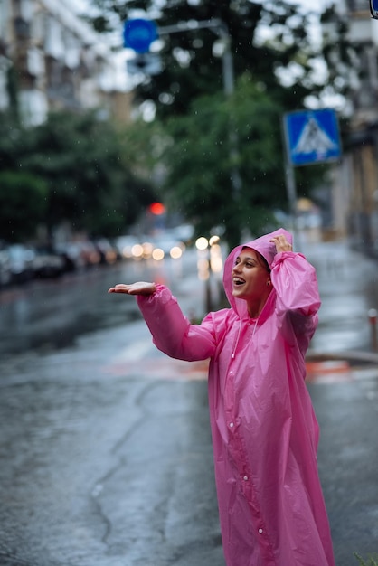 Jovem sorridente com capa de chuva enquanto desfruta de um dia chuvoso