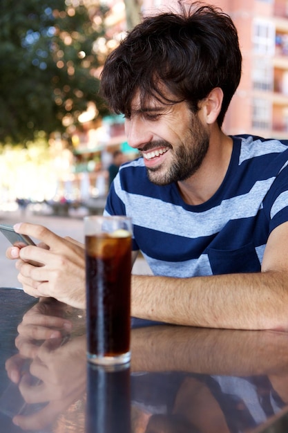 Jovem sorridente com celular no café ao ar livre