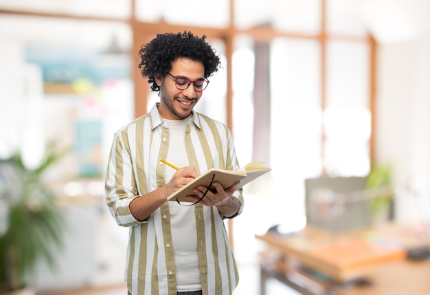 jovem sorridente com diário e lápis no escritório