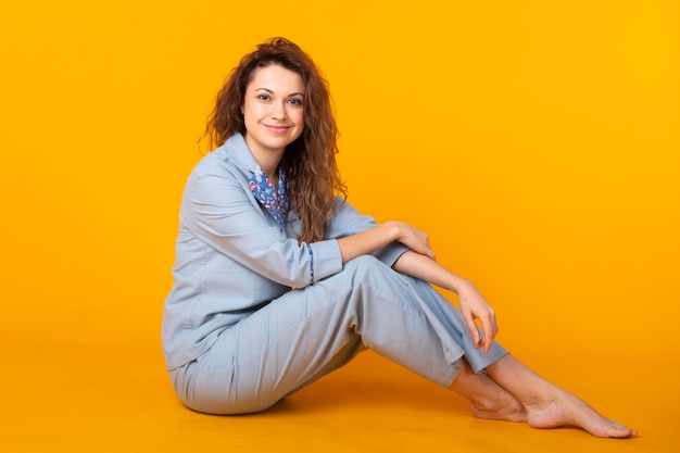 Jovem sorridente com pijama em casa, posando enquanto descansava em casa, isolada na parede amarela