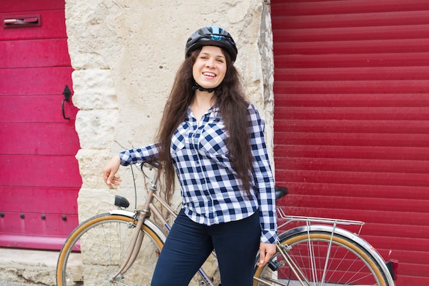 Jovem sorridente com uma bicicleta olhando a câmera