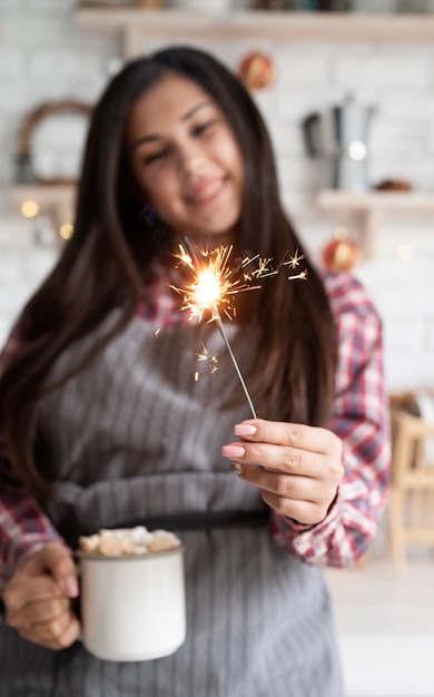 Jovem sorridente com uma xícara de chocolate quente de marshmallow e um espumante