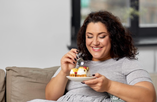 jovem sorridente comendo bolo em casa