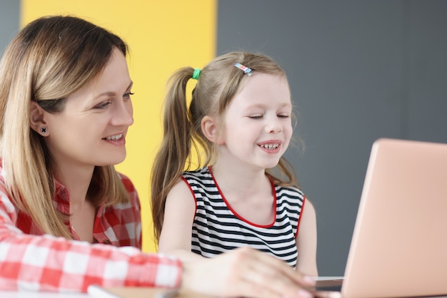 Jovem sorridente dando aulas com a criança no laptop