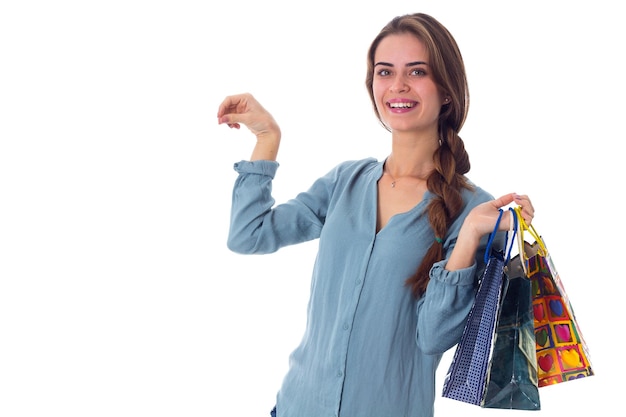 Jovem sorridente de blusa segurando sacolas de compras coloridas e segurando algo na mão