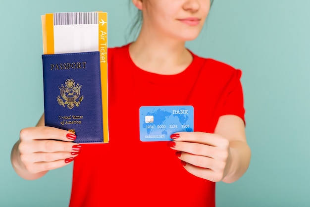 Jovem sorridente e animada estudante segurando o passaporte e o cartão de crédito do cartão de embarque