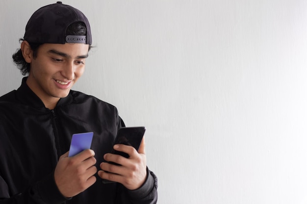 Jovem sorridente e animado fazendo uma compra online com seu cartão de crédito em seu smartphone