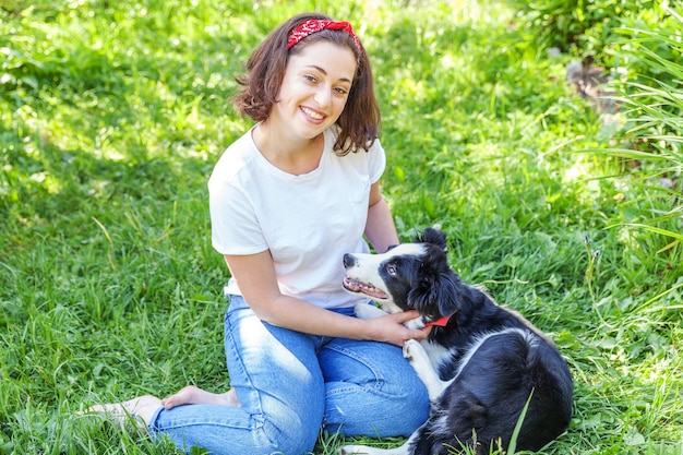 Jovem sorridente e atraente brincando com o filhote de cachorro border collie no jardim de verão