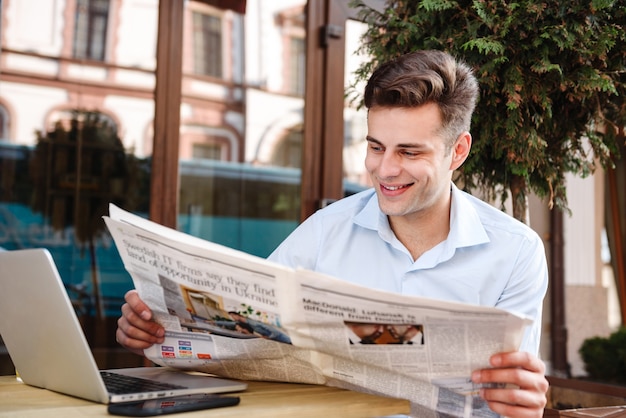 Jovem sorridente e elegante em uma camisa lendo jornal