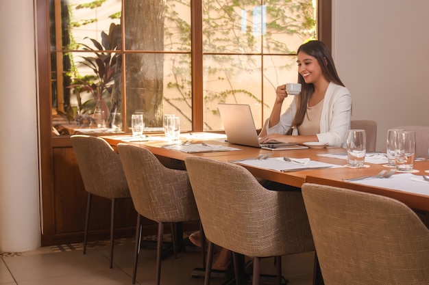 Jovem sorridente empresária tomando um café no restaurante