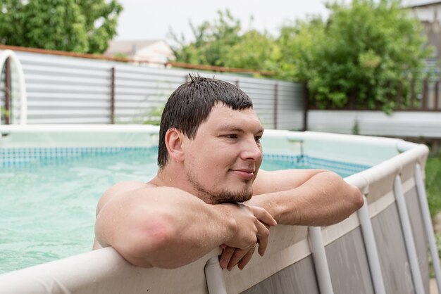 Jovem sorridente encostado na beira da piscina