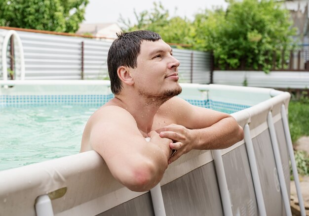 Jovem sorridente encostado na beira da piscina