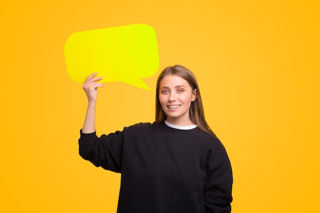 Jovem sorridente está segurando um discurso de bolha. Tema amarelo.