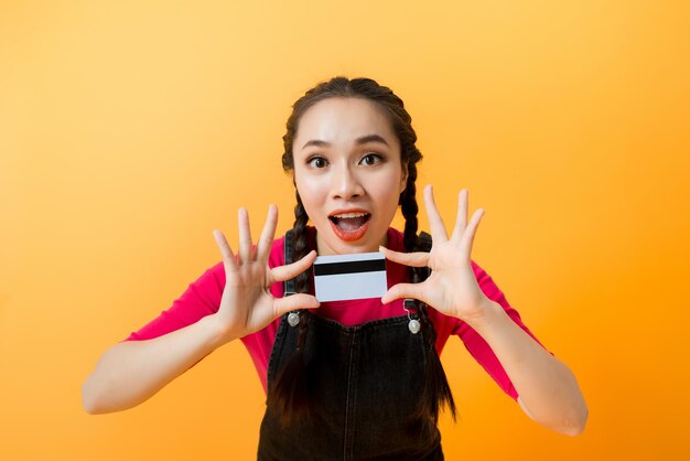 Jovem sorridente linda mulher asiática apresentando cartão de crédito na mão mostrando confiança e confiança para fazer o pagamento