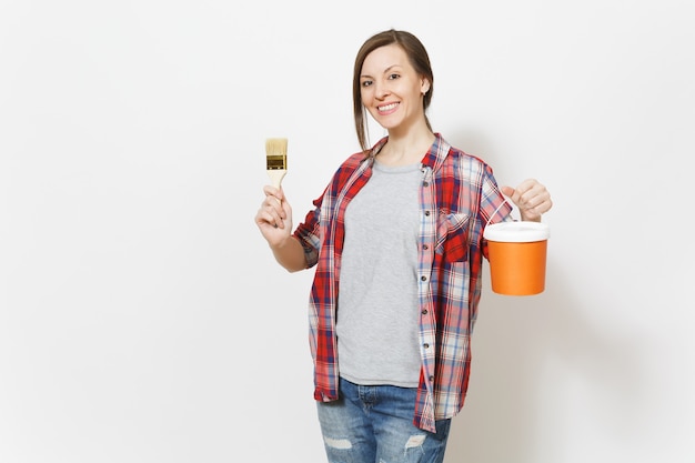 Jovem sorridente linda mulher em roupas casuais, segurando o pincel e o balde de tinta, isolado no fundo branco. Instrumentos, acessórios, ferramentas para sala de apartamento de renovação. Conceito de casa de reparo.