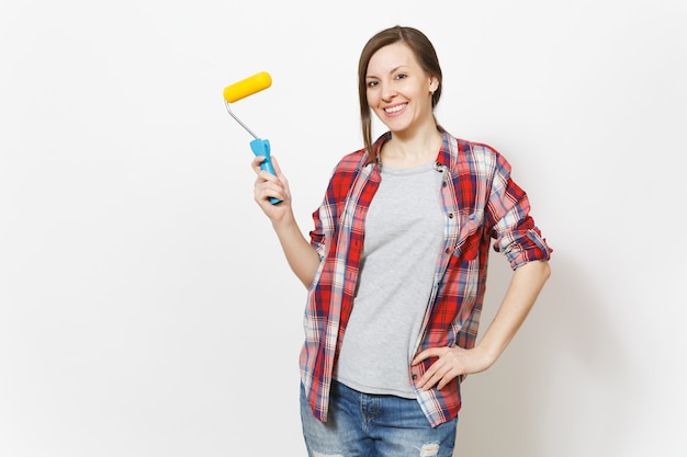 Jovem sorridente linda mulher em roupas casuais, segurando o rolo de pintura para pintura de parede isolada no fundo branco. Instrumentos, acessórios, ferramentas para sala de apartamento de renovação. Conceito de casa de reparo.