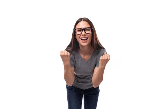 Jovem sorridente morena bonita mulher europeia vestida com uma camiseta cinzenta com uma maquete em um branco