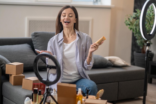 Jovem sorridente mostrando novos produtos de beleza online