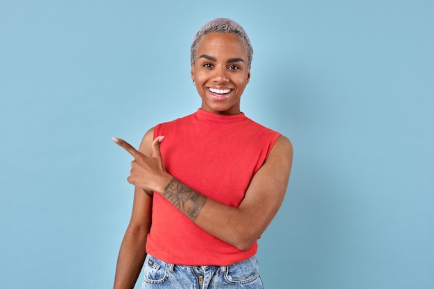 Foto jovem sorridente mulher afro-americana aponta o dedo para o lado está no estúdio