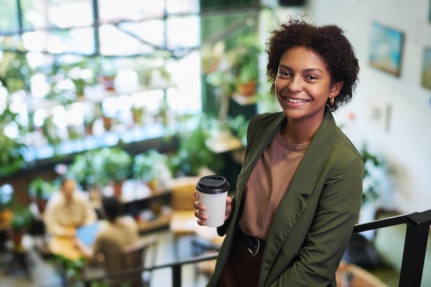 Jovem sorridente mulher de negócios afro-americana com uma chávena de café