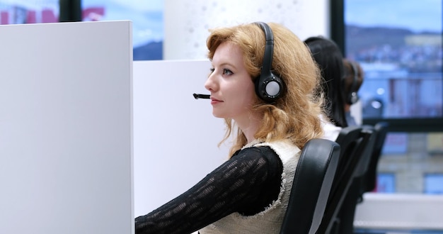 jovem sorridente operador de call center feminino fazendo seu trabalho com um fone de ouvido