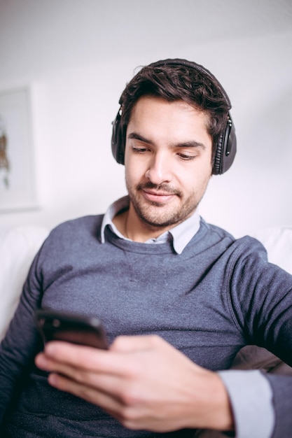 Jovem sorridente ouvindo música em fones de ouvido em casa
